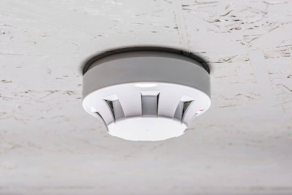 smoke detector of fire alarm on white ceiling at home